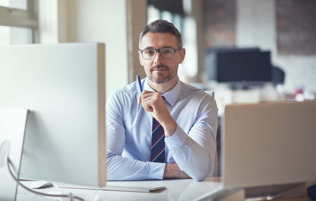 portrait, pen and business man by computer for advisory service, finance and experience in office. face, serious and expert manager, professional or tax consultant with glasses at enterprise in usa